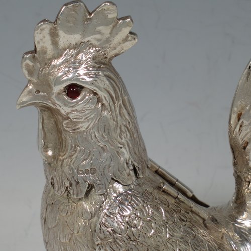 An Antique Edwardian Sterling Silver model of a Rooster or Cockerel bird, having realistically hand-chased feathers, a pull-off head with garnet eyes, with hinged wings, and cast feet. Imported and having hallmarks for Chester in 1903. The dimensions of this fine hand-made antique silver cockerel rooster model are height 14 cms (5.5 inches), length 13 cms (5 inches), width 5.5 cms (2.25 inches), and it weighs approx. 250g (8 troy ounces).