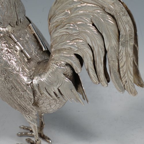 An Antique Edwardian Sterling Silver model of a Rooster or Cockerel bird, having realistically hand-chased feathers, a pull-off head with garnet eyes, with hinged wings, and cast feet. Imported and having hallmarks for Chester in 1903. The dimensions of this fine hand-made antique silver cockerel rooster model are height 14 cms (5.5 inches), length 13 cms (5 inches), width 5.5 cms (2.25 inches), and it weighs approx. 250g (8 troy ounces).