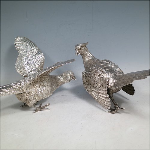 A Sterling Silver large pair of cast pheasants, showing a male and female bird in realistic traditional poses, finely detailed with hand-chased bodies and tail feathers. Made by C. J. Vanders of London in 2000. The dimensions of these fine hand-made sterling silver pheasants are length of male bird 28 cms (11 inches), height 17 cms (6.75 inches), and they weigh a total approx. 1,945g (63 troy ounces).   
