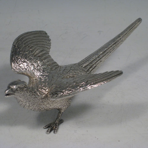 Sterling silver pair of cast pheasants, showing two male cock birds, with realistically hand-chased feathers. Made by A.E. Jones of Birmingham in 1975. The dimensions of these sterling silver pheasants are: length of startled bird out 16.5 cms (6.5 inches), height of resting bird 8 cms (3 inches), width of startled bird 10 cms (4 inches). Weight approx. 483g (15.6 troy ounces).