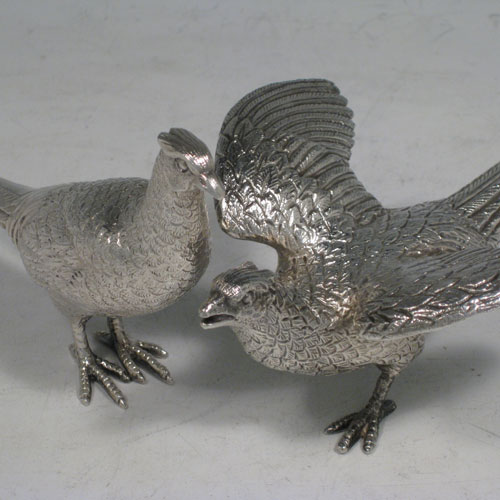 Sterling silver pair of cast pheasants, showing two male cock birds, with realistically hand-chased feathers. Made by A.E. Jones of Birmingham in 1975. The dimensions of these sterling silver pheasants are: length of startled bird out 16.5 cms (6.5 inches), height of resting bird 8 cms (3 inches), width of startled bird 10 cms (4 inches). Weight approx. 483g (15.6 troy ounces).