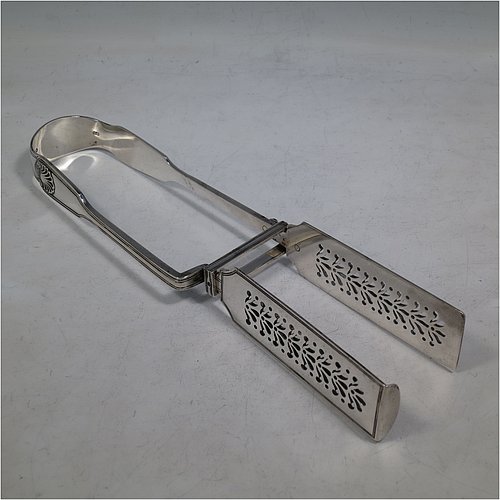 An Antique Victorian Sterling Silver pair of asparagus serving tongs, in the Fiddle, Thread, & Shell pattern, having hand-pierced blades, and original retaining guard with screws. Made by George Adams of London in 1856. The dimensions of this fine pair of antique silver asparagus servers are length 25 cms (9.75 inches), and they weigh approx. 223g (7.2 troy ounces). Please note that this item is crested.   