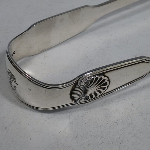 An Antique Victorian Sterling Silver pair of asparagus serving tongs, in the Fiddle, Thread, & Shell pattern, having hand-pierced blades, and original retaining guard with screws. Made by George Adams of London in 1856. The dimensions of this fine pair of antique silver asparagus servers are length 25 cms (9.75 inches), and they weigh approx. 223g (7.2 troy ounces). Please note that this item is crested.