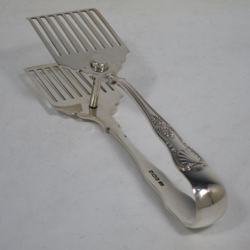 A handsome Sterling Silver pair of asparagus serving tongs, in the Kings pattern, having plain hand-pierced blades, and original retaining guard with screw. Made by George Hancock of Sheffield in 1928. The dimensions of this fine pair of silver asparagus servers are length 19 cms (7.5 inches), and they weigh approx. 148g (4.8 troy ounces).    
