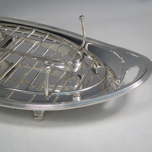 Antique Edwardian silver plated asparagus serving set, having a plain oval body, with an applied reeded border, an original wire-work serving rack, two cut-out side-handles, and sitting on four cast flange feet. Together with a matching pair of tongs made by John Grinsell of Sheffield in ca. 1900. The dimensions of this fine hand-made silver-plated asparagus serving set are length 43 cms (17 inches), and width, 21.5 cms (8.5 inches).