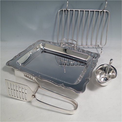 An Antique Edwardian Silver Plated asparagus serving set, having a plain rectangular body, with an applied and shaped reeded border, a wire-work serving rack, a sauce boat sat in a frame with loop handle, a pair of asparagus server tongs, and all sitting on a base with four button feet. All pieces were made by the Atkins Brothers of Sheffield in ca. 1900. The dimensions of this fine hand-made silver-plated asparagus serving set are length 29 cms (11.5 inches), and width, 23 cms (9 inches).    