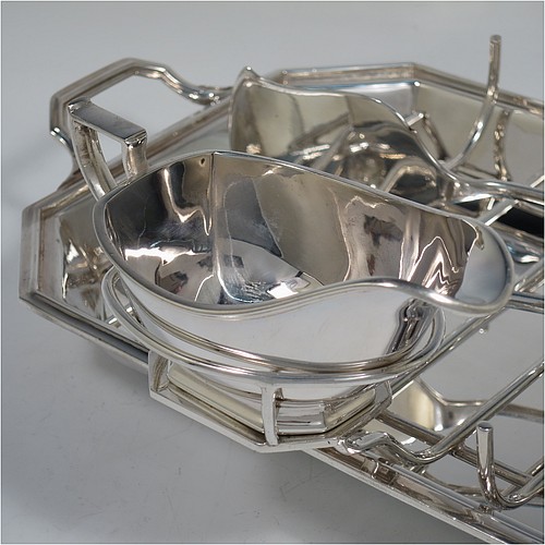 An Art Deco style Silver Plated asparagus serving set, having a plain elongated octagonal body, with an applied reeded border and two cast side-handles, a wire-work serving rack, a sauce boat sat in a frame with loop handle, a pair of asparagus server tongs, and all sitting on a flat base. All pieces are original and were made in England, circa 1930. The dimensions of this fine hand-made silver-plated Art Deco asparagus serving set are length 32.5 cms (12.75 inches), and width, 20 cms (8 inches).