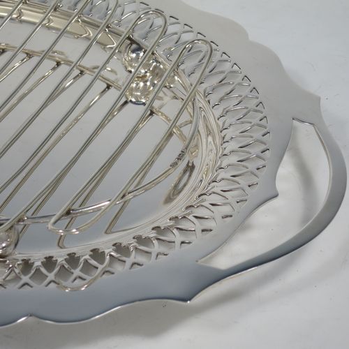 A pretty Antique Victorian Sterling Silver asparagus serving set, having a shaped oval body with cut out handles, a hand-cut Chippendale outer border with hand-pierced inner border of geometrical decoration, an original wire-work serving rack with four ball feet, and all sitting on a base with four cushion feet. Made by William Hutton and Sons of Sheffield in 1900. The dimensions of this fine hand-made antique silver asparagus serving set are length 35 cms (13.75 inches), and width 23.5 cms (9.25 inches), and with a total weight of approx. 925g (30 troy ounces).