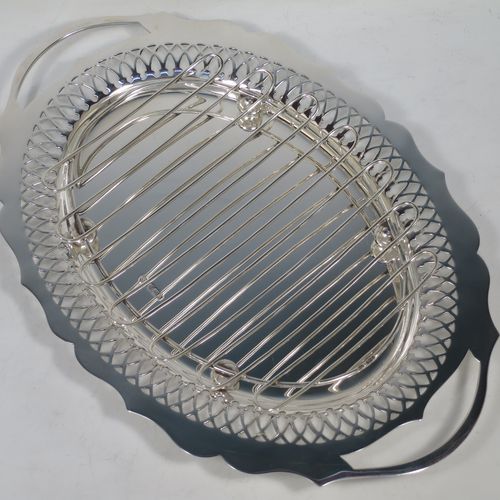 A pretty Antique Victorian Sterling Silver asparagus serving set, having a shaped oval body with cut out handles, a hand-cut Chippendale outer border with hand-pierced inner border of geometrical decoration, an original wire-work serving rack with four ball feet, and all sitting on a base with four cushion feet. Made by William Hutton and Sons of Sheffield in 1900. The dimensions of this fine hand-made antique silver asparagus serving set are length 35 cms (13.75 inches), and width 23.5 cms (9.25 inches), and with a total weight of approx. 925g (30 troy ounces).