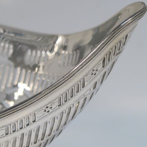A beautiful Antique Georgian Irish Sterling Silver bread or fruit basket, having an oval body with hand-pierced neoclassical and geometrical style  decoration, an applied reeded border, and all sitting on a plain oval pedestal foot. This pretty antique silver fruit or bread basket was made by Michael Homer of Dublin, Ireland, in ca. 1790. The dimensions of this fine hand-made Irish Georgian silver basket are length 30 cms (11.75 inches), width 15 cms (6 inches), height 15 cms (6 inches), and it weighs approx. 410g (13.2 troy ounces).   