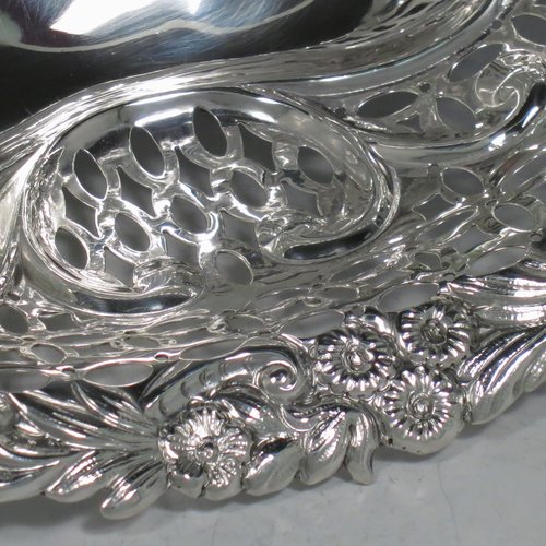 An Antique Edwardian pair of Sterling silver table baskets, having oval bodies with hand-pierced scroll-work decoration, with hand-chased floral borders, and sitting on matching pierced & scroll feet. Made by Charles Boyton of London in 1902. The dimensions of this fine pair of antique silver baskets are length 27 cms (10.75 inches), width 18.5 cms (7.25 inches), height 9 cms (3.5 inches), and they weigh a total of approx. 586g (19 troy ounces).