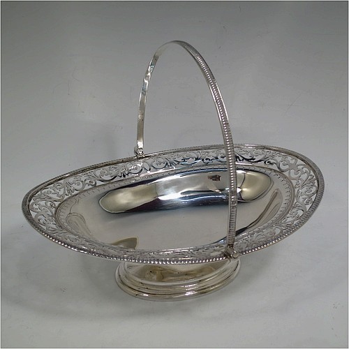 A very pretty Antique Victorian Sterling Silver basket, having an oval body with an applied gadroon border, all hand-pierced with floral and scroll decoration, a hinged swing handle, and all sitting on an oval stepped pedestal foot. Made by J.H. and H. Barraclough of London in 1899. The dimensions of this fine hand-made antique silver basket are height 21 cms (8.25 inches), length 26.5 cms (10.5 inches), width 20 cms (8 inches), and it weighs approx. 548g (17.7 troy ounces).    