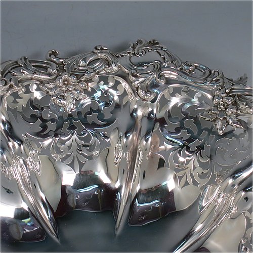 An Antique early Victorian large Sterling Silver table basket, having a round body with hand-pierced floral decoration within melon fluted panels, an applied cast floral and scroll border, and sitting on a melon fluted pedestal foot. Made by the Barnard Brothers of London in 1845. The dimensions of this fine hand-made antique silver basket are diameter 36 cms (14.25 inches), height 11 cms (4.25 inches), and it weighs approx. 1,082g (35 troy ounces).