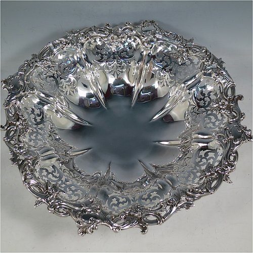 An Antique early Victorian large Sterling Silver table basket, having a round body with hand-pierced floral decoration within melon fluted panels, an applied cast floral and scroll border, and sitting on a melon fluted pedestal foot. Made by the Barnard Brothers of London in 1845. The dimensions of this fine hand-made antique silver basket are diameter 36 cms (14.25 inches), height 11 cms (4.25 inches), and it weighs approx. 1,082g (35 troy ounces).