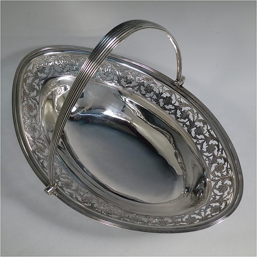 A very pretty Antique Georgian Sterling Silver basket, having an oval body with an applied reeded border, with an upper band of hand-engraved and hand-pierced floral work, a hinged and reeded swing handle, all sitting on a geometrically hand-pierced collet foot. Made by Thomas Harper I of London in 1796. The dimensions of this fine hand-made antique silver basket are height 28 cms (11 inches), length 37 cms (14.5 inches), width 26 cms (10.25 inches), and it weighs approx. 792g (25.5 troy ounces). Please note that this basket is crested.