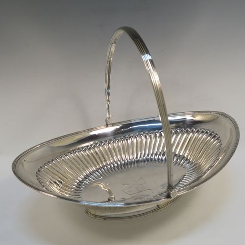 A very handsome Antique Georgian Sterling Silver basket, having an oval body with an applied reeded border, with hand-chased fluted decoration, a hinged and reeded swing handle, all sitting on a plain oval collet foot. This elegant antique silver basket was made by Joseph Scammell of London in 1795. The dimensions of this fine hand-made antique silver basket are height 28 cms (11 inches), length 37 cms (14.5 inches), width 26 cms (10.25 inches), and it weighs approx. 899g (29 troy ounces). Please note that this basket is crested.   