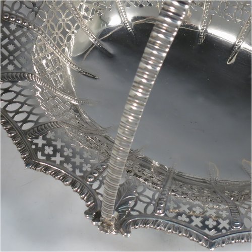 An Antique Georgian Sterling Silver basket, having an oval body with an applied shaped gadroon border, with hand-pierced panels separated by bands of bead-work, a hinged swing handle, and all sitting on a a matching pierced foot. Made by Edward Aldridge of London in 1767. The dimensions of this fine hand-made antique silver basket are height 25 cms (9.75 inches), length 37 cms (14.5 inches), width 31 cms (12.25 inches), and it weighs approx. 900g (29 troy ounces).