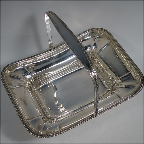 An Antique Edwardian Sterling Silver basket, having a rectangular body, with an applied gadroon border, a hinged and swing handle with gadroon edges, all sitting on a pedestal foot. Made by the Dixon Brothers of Sheffield in 1910. The dimensions of this fine hand-made antique silver basket are height 23 cms (9 inches), length 27.5 cms (10.75 inches), width 21 cms (8.25 inches), and it weighs approx. 746g (24 troy ounces).