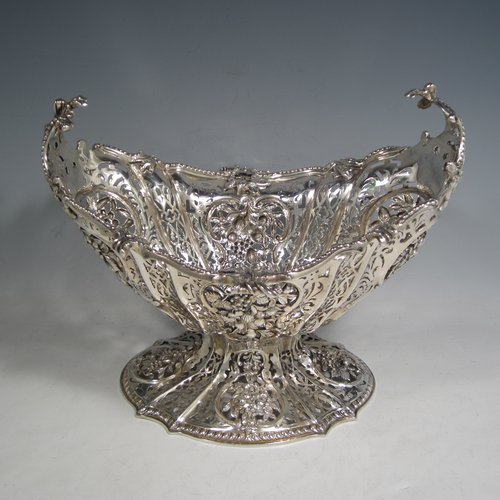 Antique Victorian large sterling silver table basket, in an asymmetrical Art Nouveau style, having an oval hand-pierced body with hand-chased floral decoration, with cast floral and bead-edged borders, and sitting on a matching pedestal foot. Made by Martin Hall & Co., of Sheffield in 1892. The dimensions of this fine hand-made silver basket are length 27.5 cms (10.75 inches), width 23 cms (9 inches), height 21.5 cms (8.5 inches), and it weighs approx. 1,100g (35.5 troy ounces).   