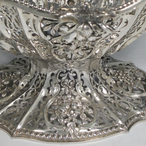 Antique Victorian large sterling silver table basket, in an asymmetrical Art Nouveau style, having an oval hand-pierced body with hand-chased floral decoration, with cast floral and bead-edged borders, and sitting on a matching pedestal foot. Made by Martin Hall & Co., of Sheffield in 1892. The dimensions of this fine hand-made silver basket are length 27.5 cms (10.75 inches), width 23 cms (9 inches), height 21.5 cms (8.5 inches), and it weighs approx. 1,100g (35.5 troy ounces).
