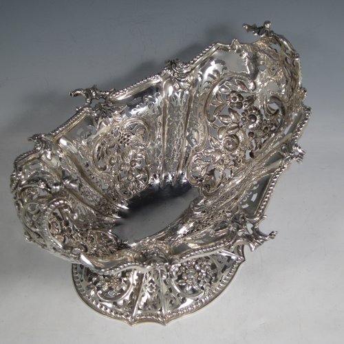 Antique Victorian large sterling silver table basket, in an asymmetrical Art Nouveau style, having an oval hand-pierced body with hand-chased floral decoration, with cast floral and bead-edged borders, and sitting on a matching pedestal foot. Made by Martin Hall & Co., of Sheffield in 1892. The dimensions of this fine hand-made silver basket are length 27.5 cms (10.75 inches), width 23 cms (9 inches), height 21.5 cms (8.5 inches), and it weighs approx. 1,100g (35.5 troy ounces).