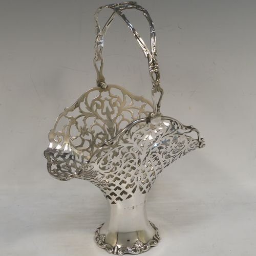 A very pretty Antique Edwardian Sterling Silver wedding style basket, having an oval body with applied scroll borders and hand-pierced floral and geometrical decoration, and a matching swing handle, all sitting on a pedestal foot. This beautiful silver wedding basket was made in Birmingham in 1910. The dimensions of this fine hand-made antique silver wedding basket are height 23 cms (9 inches), length 15 cms (6 inches), width 11.5 cms (4.5 inches), and it weighs approx. 243g (7.8 troy ounces).   