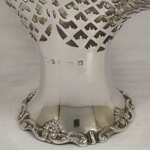 A very pretty Antique Edwardian Sterling Silver wedding style basket, having an oval body with applied scroll borders and hand-pierced floral and geometrical decoration, and a matching swing handle, all sitting on a pedestal foot. This beautiful silver wedding basket was made in Birmingham in 1910. The dimensions of this fine hand-made antique silver wedding basket are height 23 cms (9 inches), length 15 cms (6 inches), width 11.5 cms (4.5 inches), and it weighs approx. 243g (7.8 troy ounces).