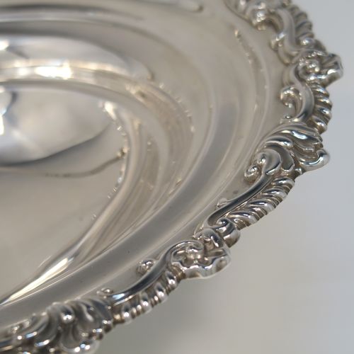 A handsome Antique Georgian Regency style sterling silver basket, having a plain bellied oval body, with an applied shell and scroll border, a hinged and swing handle, all sitting on an oval pedestal foot with an applied gadroon border. This elegant antique silver basket was made by S. C. Younge and Co., of Sheffield in 1815. The dimensions of this fine hand-made Regency silver basket are height 25 cms (10 inches), length 33 cms (13 inches), width 28 cms (11 inches), and it weighs approx. 1,189g (38 troy ounces).   