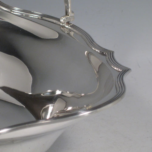 An elegant Antique Edwardian Sterling Silver table basket, having a plain oval body with shaped border and applied reeded edge, a hinged reeded handle, and sitting on a collet foot with reeded border. This handsome silver basket was made by Charles Stuart Harris of London in 1903. The dimensions of this fine hand-made antique silver basket are height inc. handle 20 cms (8 inches), length 23 cms (9 inches), 19 cms (7.5 inches), and it weighs approx. 339g (11 troy ounces).