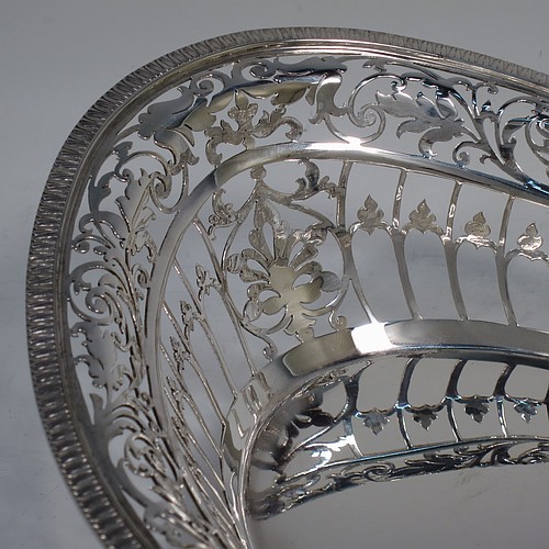 A very pretty Sterling Silver basket, having an oval body with an applied gadroon border, all hand-pierced with floral and scroll decoration, a hinged and pierced swing handle, and all sitting on four cast flange feet. Made by James Dixon and Sons of Sheffield in 1927. The dimensions of this fine hand-made silver basket are height 20 cms (8 inches), length 28 cms (11 inches), width 20 cms (8 inches), and it weighs approx. 548g (17.7 troy ounces).