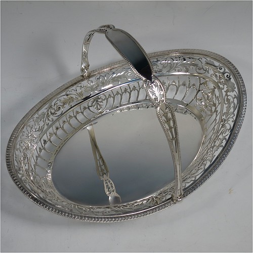 A very pretty Sterling Silver basket, having an oval body with an applied gadroon border, all hand-pierced with floral and scroll decoration, a hinged and pierced swing handle, and all sitting on four cast flange feet. Made by James Dixon and Sons of Sheffield in 1927. The dimensions of this fine hand-made silver basket are height 20 cms (8 inches), length 28 cms (11 inches), width 20 cms (8 inches), and it weighs approx. 548g (17.7 troy ounces).