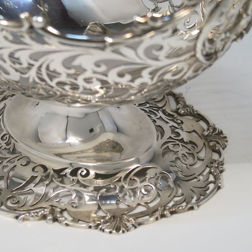 A large and very pretty Antique Sterling silver fruit basket, having an oval body with hand-pierced floral and scroll decoration, applied cast scroll and floral borders, with two cast scroll and shell flying side-handles, and all sitting on a matching pedestal foot. This beautiful antique silver basket was made by Jackson and Fullerton of London in 1912. The dimensions of this fine antique silver basket are length 27 cms (10.5 inches), width 18 cms (7 inches), height 22 cms (8.75 inches), and it weighs approx. 1,062g (34 troy ounces).