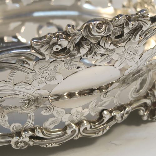 A very pretty Antique Scottish Edwardian Sterling silver small fruit basket, having an oval body with hand-pierced and engraved floral and scroll decoration, applied cast scroll and floral borders, and all sitting on four cast foliate feet. This beautiful antique silver basket was made by Hamilton and Inches of Edinburgh in 1904. The dimensions of this fine antique silver basket are length 20 cms (8 inches), width 17 cms (6.75 inches), height 10 cms (4 inches), and it weighs approx. 452g (14.6 troy ounces).   