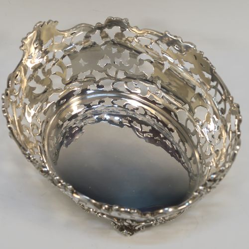 A very pretty Antique Scottish Edwardian Sterling silver small fruit basket, having an oval body with hand-pierced and engraved floral and scroll decoration, applied cast scroll and floral borders, and all sitting on four cast foliate feet. This beautiful antique silver basket was made by Hamilton and Inches of Edinburgh in 1904. The dimensions of this fine antique silver basket are length 20 cms (8 inches), width 17 cms (6.75 inches), height 10 cms (4 inches), and it weighs approx. 452g (14.6 troy ounces).   