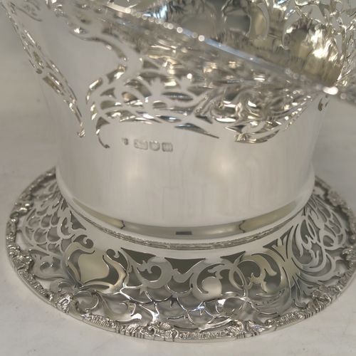 A large and very pretty Antique Edwardian Sterling Silver wedding style basket, having a round body with applied floral borders and hand-pierced floral and scroll decoration, a matching swing handle, and all sitting on a pedestal foot. This beautiful silver wedding basket was made by Jackson and Fullerton of London in 1907. The dimensions of this fine hand-made antique silver wedding basket are height 31 cms (12.25 inches), length 27 cms (10.75 inches), width 20 cms (8 inches), and it weighs approx. 633g (20.4 troy ounces).