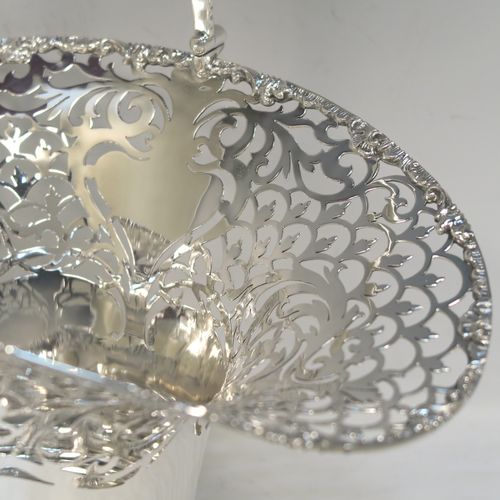 A large and very pretty Antique Edwardian Sterling Silver wedding style basket, having a round body with applied floral borders and hand-pierced floral and scroll decoration, a matching swing handle, and all sitting on a pedestal foot. This beautiful silver wedding basket was made by Jackson and Fullerton of London in 1907. The dimensions of this fine hand-made antique silver wedding basket are height 31 cms (12.25 inches), length 27 cms (10.75 inches), width 20 cms (8 inches), and it weighs approx. 633g (20.4 troy ounces).