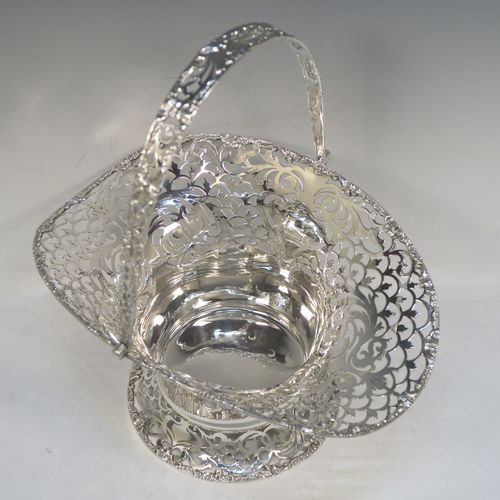A large and very pretty Antique Edwardian Sterling Silver wedding style basket, having a round body with applied floral borders and hand-pierced floral and scroll decoration, a matching swing handle, and all sitting on a pedestal foot. This beautiful silver wedding basket was made by Jackson and Fullerton of London in 1907. The dimensions of this fine hand-made antique silver wedding basket are height 31 cms (12.25 inches), length 27 cms (10.75 inches), width 20 cms (8 inches), and it weighs approx. 633g (20.4 troy ounces).