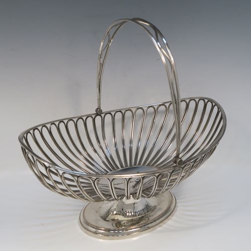 A handsome Antique Georgian Old Sheffield Silver-Plated basket, having an oval body all formed from wire-work decoration, a hinged wire-work swing handle, and all sitting on a plain oval stepped pedestal foot. This elegant antique basket was made  in ca. 1790. The dimensions of this fine hand-made antique 18th Century Old Sheffield Silver-Plated basket are height (inc. handle) 30.5 cms (12 inches), length 32 cms (12.5 inches), and width 21 cms (8.25 inches).   