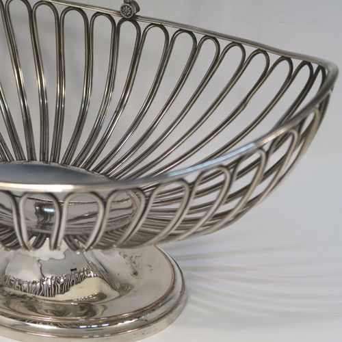 A handsome Antique Georgian Old Sheffield Silver-Plated basket, having an oval body all formed from wire-work decoration, a hinged wire-work swing handle, and all sitting on a plain oval stepped pedestal foot. This elegant antique basket was made in ca. 1790. The dimensions of this fine hand-made antique 18th Century Old Sheffield Silver-Plated basket are height (inc. handle) 30.5 cms (12 inches), length 32 cms (12.5 inches), and width 21 cms (8.25 inches).