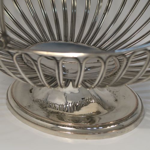 A handsome Antique Georgian Old Sheffield Silver-Plated basket, having an oval body all formed from wire-work decoration, a hinged wire-work swing handle, and all sitting on a plain oval stepped pedestal foot. This elegant antique basket was made in ca. 1790. The dimensions of this fine hand-made antique 18th Century Old Sheffield Silver-Plated basket are height (inc. handle) 30.5 cms (12 inches), length 32 cms (12.5 inches), and width 21 cms (8.25 inches).