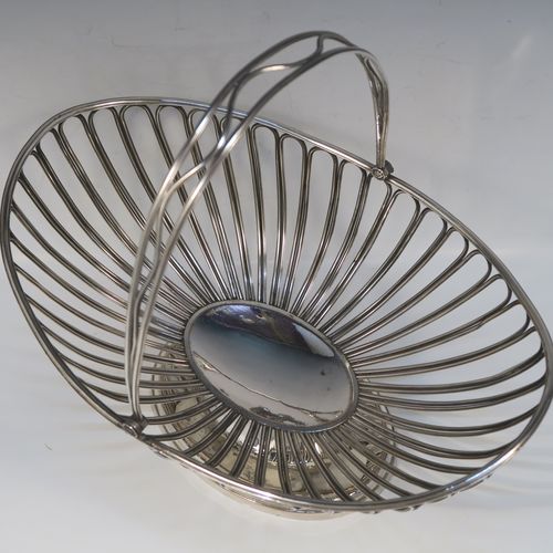 A handsome Antique Georgian Old Sheffield Silver-Plated basket, having an oval body all formed from wire-work decoration, a hinged wire-work swing handle, and all sitting on a plain oval stepped pedestal foot. This elegant antique basket was made in ca. 1790. The dimensions of this fine hand-made antique 18th Century Old Sheffield Silver-Plated basket are height (inc. handle) 30.5 cms (12 inches), length 32 cms (12.5 inches), and width 21 cms (8.25 inches).