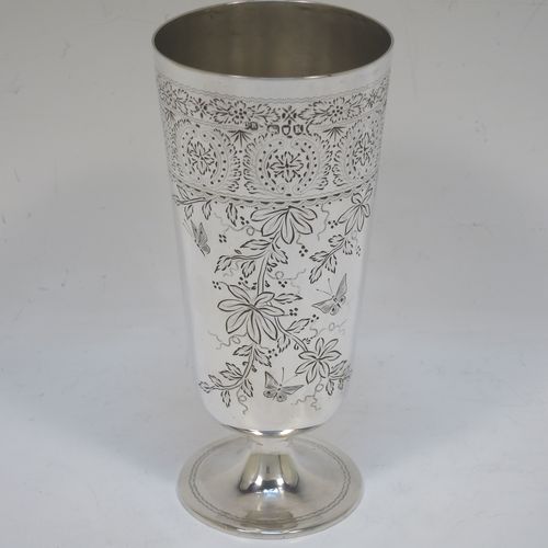 A very pretty Antique Victorian Sterling Silver beaker, having a round straight-sided body with tapering sides, with hand-engraved floral decoration and butterflies, and vacant cartouches either side, and all sitting on a round pedestal foot. Made by Charles Boyton of London in 1885. The dimensions of this fine hand-made antique silver beaker are height 14 cms (5.5 inches), diameter at top 6.5 cms (2.5 inches), and it weighs approx. 171g (5.5 troy ounces).  