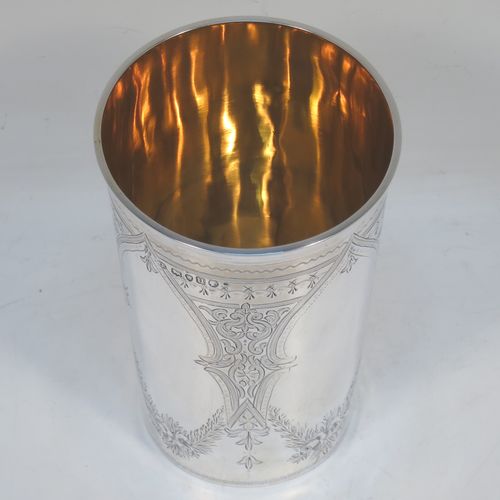 A very pretty and large Antique Victorian Sterling Silver beaker, having a round straight-sided body with tapering sides, with hand-engraved scroll and floral decoration surrounding four vacant cartouches, a gold-gilt interior, and all sitting on a flat base. Made by William Evans of London in 1875. The dimensions of this fine hand-made antique silver beaker are height 12.5 cms (5 inches), diameter at top 8 cms (3 inches), and it weighs approx. 170g (5.5 troy ounces).