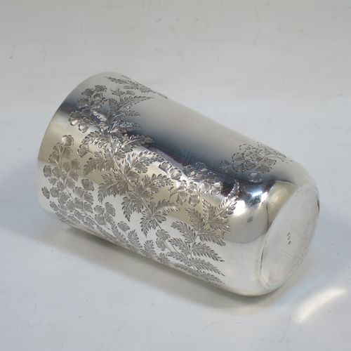A very pretty Antique Victorian Sterling Silver beaker, having a round straight-sided body with tapering sides and a tucked under base, with hand-engraved ferns and gingko leaves surrounding two vacant cartouches either side, a gold-gilt interior and all sitting on a flat base. Made by F. C. W. Ltd., of London in 1889. The dimensions of this fine hand-made antique silver beaker are height 9 cms (3.5 inches), diameter at top 6 cms (2.25 inches), and it weighs approx. 75g (2.4 troy ounces).
