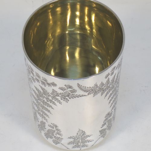 A very pretty Antique Victorian Sterling Silver beaker, having a round straight-sided body with tapering sides and a tucked under base, with hand-engraved ferns and gingko leaves surrounding two vacant cartouches either side, a gold-gilt interior and all sitting on a flat base. Made by F. C. W. Ltd., of London in 1889. The dimensions of this fine hand-made antique silver beaker are height 9 cms (3.5 inches), diameter at top 6 cms (2.25 inches), and it weighs approx. 75g (2.4 troy ounces).