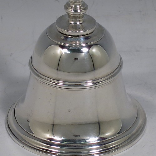 A Sterling Silver Georgian style table bell having a plain round body with applied reeded borders, a cast baluster handle, and an original silver clapper. Made by Carrington and Co., of London in 1929. The dimensions of this fine hand-made silver table bell are height 10.5 cms (4.25 inches), diameter at base 6 cms (2.3 inches), and it weighs approx. 165g (5.3 troy ounces).