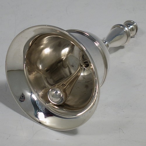 A Sterling Silver Georgian style table bell having a plain round body with applied reeded borders, a cast baluster handle, and an original silver clapper. Made by Carrington and Co., of London in 1929. The dimensions of this fine hand-made silver table bell are height 10.5 cms (4.25 inches), diameter at base 6 cms (2.3 inches), and it weighs approx. 165g (5.3 troy ounces).