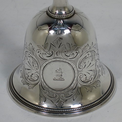 A very pretty Antique Victorian Sterling Silver table bell having a round baluster body with hand-engraved floral and scroll decoration, a tear-drop shaped handle with ball finial, with applied bead-edged borders, and an original silver clapper. Made by Hayne and Cater of London in 1863. The dimensions of this fine hand-made antique silver table bell are height 14 cms (5.5 inches), diameter at base 7 cms (2.75 inches), and it weighs approx. 132g (4.25 troy ounces). Please note that this item is crested.