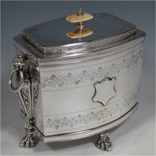 An Antique Victorian Silver Plated biscuit box, having a Neoclassical style rectangular shaped body with straight sides, applied bead-edged borders, with two bands of hand-engraving above and below a vacant cartouche, a hinged lid with ivory finial, two cast lion-mask ring handles, and all sitting on four cast lions-paw feet. Made in ca. 1880. The dimensions of this fine hand-made silver-plated biscuit boxr are height 18 cms (7 inches), length 21 cms (8.25 inches), and width 15 cms (6 inches).  