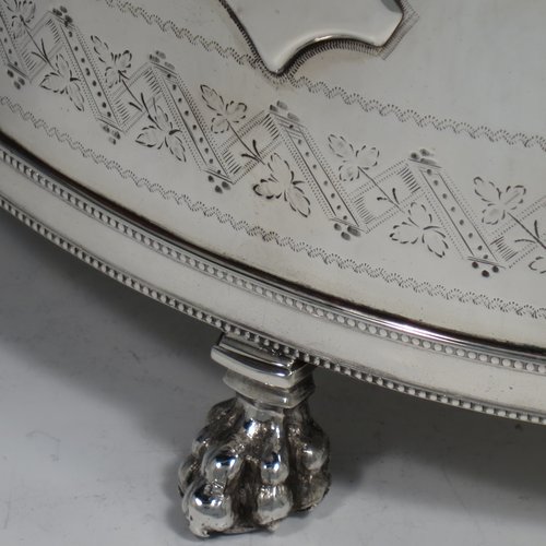 An Antique Victorian Silver Plated biscuit box, having a Neoclassical style rectangular shaped body with straight sides, applied bead-edged borders, with two bands of hand-engraving above and below a vacant cartouche, a hinged lid with ivory finial, two cast lion-mask ring handles, and all sitting on four cast lions-paw feet. Made in ca. 1880. The dimensions of this fine hand-made silver-plated biscuit boxr are height 18 cms (7 inches), length 21 cms (8.25 inches), and width 15 cms (6 inches).